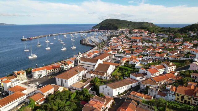 AZORES - 10.27.2025 - Great aerial footage circling counterclockwise around a harbor of Faial Island, with a view of the Montanha Do Pico volcano in the distance.