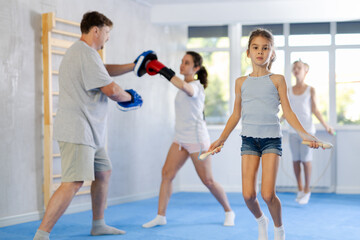 Little athletic girl trains jumping rope in studio