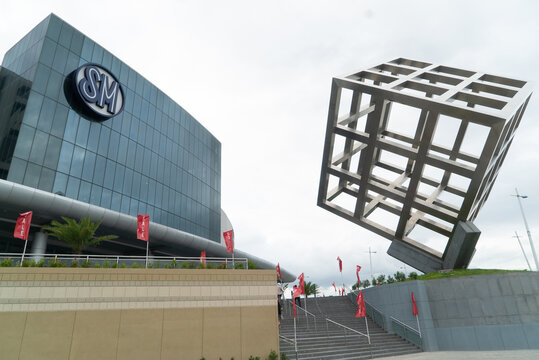 Cebu City, Cebu, Philippines - April 7, 2018: Exterior of SM seaside shopping mall with large glass building, logo and metal cube sculpture on reclaimed land