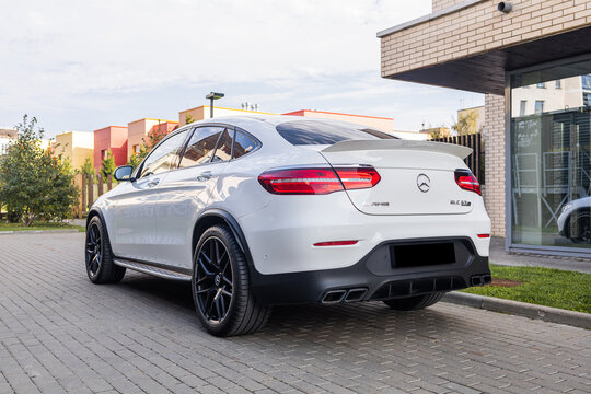 White Mercedes-Benz GLC 63 S AMG parked on cobblestone pavement near a white building with green lawn, showcasing luxury, power, and modern German SUV performance design.
