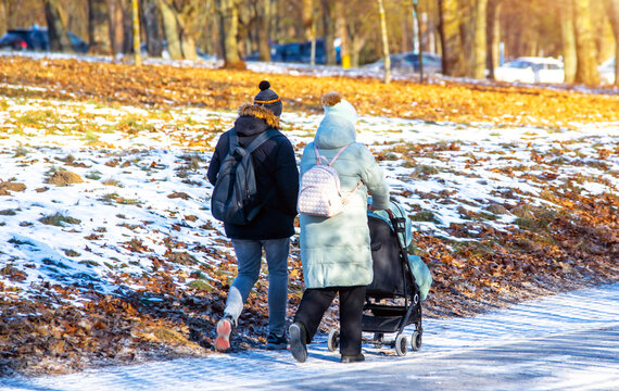 A married couple rolls a child in a wheelchair in the winter Park
