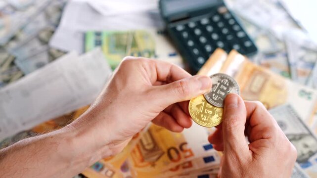 Hands shows silver and golden BTC bitcoin against the dollars and euros