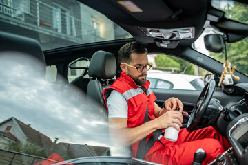 Paramamedic man hydrating in car during emergency service break