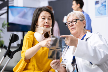 Nurse and injured patient going through treatment plan discussion for painful neck fracture. Hospital staff offering support with physiotherapy exercises and calming techniques during recovery.