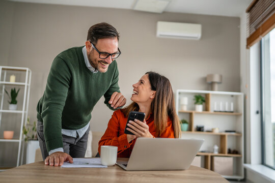 Couple collaborating on home finances using laptop and smart phone