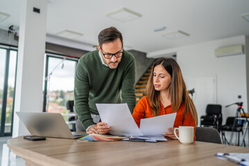 Coworkers collaborating on business project reviewing documents in office