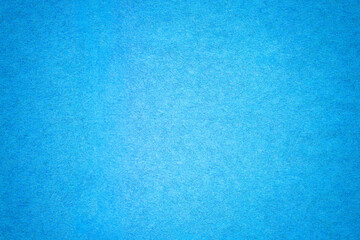 Blue paper background texture with gradient. Vintage cerulean cardboard backdrop with dark vignette border.
