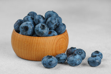 Fresh ripe blueberries in small wooden bowl on gray textured stone background. Delicious organic fruit rich in vitamins, wild berries,healthy lifestyle, natural food. Close up, macro