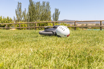 Electric unicycle with a helmet lie on the green lawn against a wooden fence