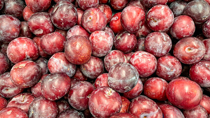 Fresh plump red plums piled together, showcasing their vibrant color and smooth texture, ideal for healthy eating and culinary uses in various dishes and desserts