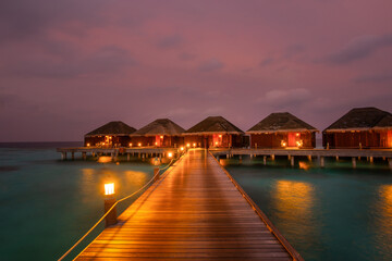 Tranquil closeup calm sea water waves with palm trees. Beautiful blue hours with bungalows....