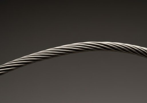 Close-up studio shot of a shiny, flexible nickel titanium alloy wire coiled against a neutral background showcasing metallic properties, industrial, laboratory, technical