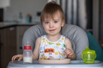 Infant girl eats deliciously while sitting at a childrens table