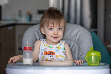 Infant girl eats deliciously while sitting at a childrens table