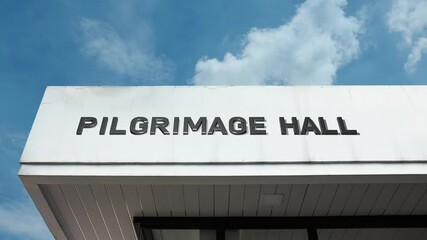 A Pilgrimage Hall word sign displayed on a religious or spiritual gathering building under a clear blue sky, symbolizing sacred journeys, communal worship, and historical sites
