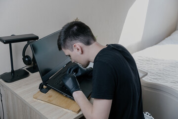 Obraz premium A young man glues stickers to a laptop keyboard with special plastic.