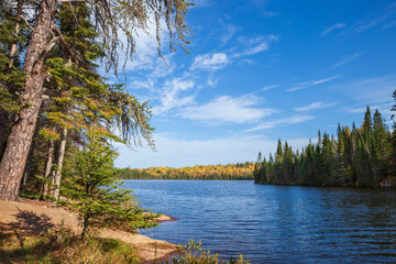 Pretty blue trout lake surrounded by hills and trees in autumn color in northern Minnesota