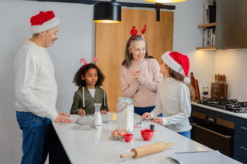 Diverse multi-generational family mixing cookie dough at kitchen island with rolling pin and flour