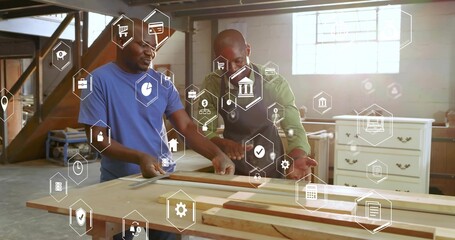 Two mature carpenters aligning wooden board in woodshop, with tape measure, ruler and digital icons