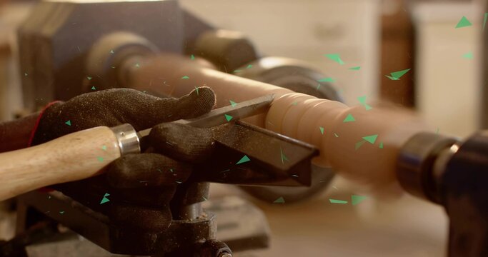Shaping wooden spindle blank on lathe at workshop, guiding chisel and scattering wood shavings
