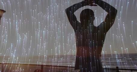 Stretching man raising arms overhead on boardwalk by metal railing at dusk, with digital light