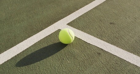 Resting tennis ball casting elongated shadow on green hardcourt, with crisp white boundary lines © vectorfusionart