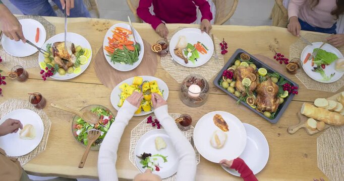 Hunger motivating diverse family passing veggies scooping corn carving turkey taking rolls at table