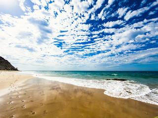 California beach and sea on a vibrant sunny day with footprints in the wet sand