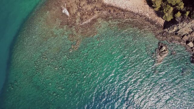 Drone view of turquoise sea and rocky coastline near Phaselis, Antalya, Turkey. Crystal clear water, sunlight reflections, and natural Mediterranean beauty.