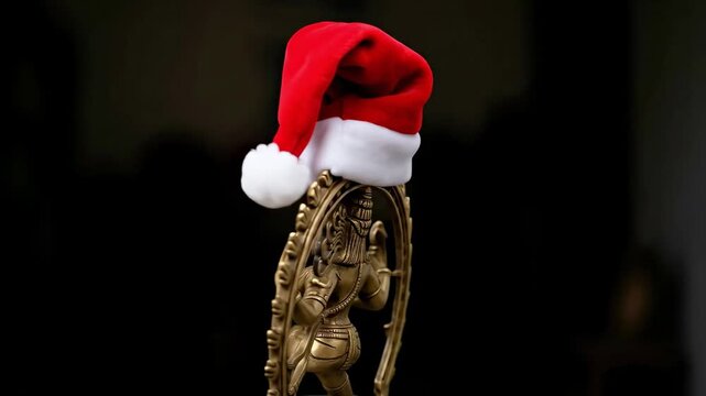 Bronze statue of Hindu deity Shiva Nataraja adorned with a festive red Santa hat, symbolizing a unique blend of spiritual traditions and holiday cheer against a dark background.