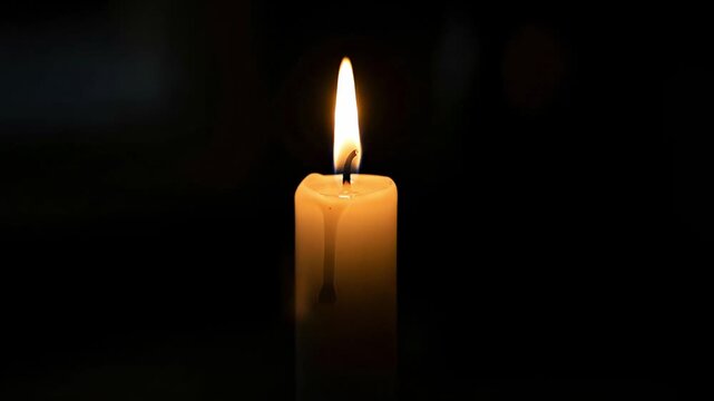 Single lit candle glowing brightly in the dark, casting a warm and peaceful light, symbolizing hope and remembrance.