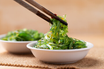 Wakame seaweed salad with sesame seed in a bowl with chopsticks © nungning20