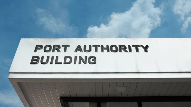 A Port Authority Building word sign displayed on a large governmental or commercial structure under a clear blue sky, symbolizing maritime regulation, trade, logistics, and coastal management