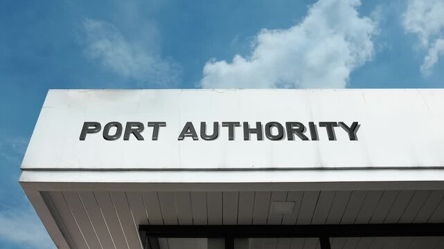 A Port Authority word sign displayed on a large governmental or commercial building under a clear blue sky, symbolizing maritime regulation, trade, logistics, and coastal management