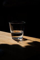 Glass of water casting shadow on wooden table