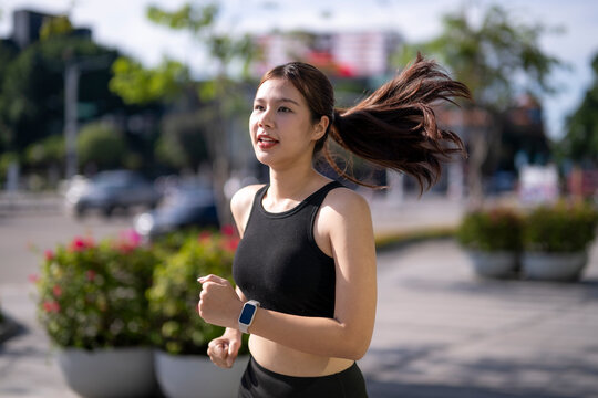 Young woman jogging outdoors wearing smartwatch for fitness