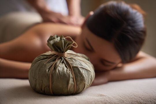 Relaxing massage therapy session with herbal poultice in serene spa setting for stress relief and rejuvenation