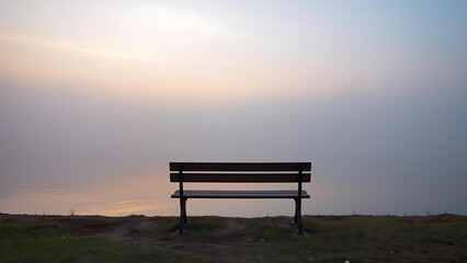 Empty wooden bench by a calm lake at dawn, soft mist and pastel sky evoke feelings of loss, nostalgia, and peace &mdash; fine art photo with emotional depth and poetic stillness.