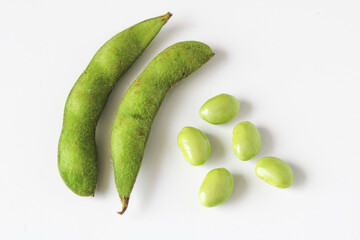 Shelled and unshelled edamame pods, isolated on white background.