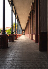 Long perspective view of a historical architectural corridor with columnsSymmetrical corridor with repeating columns and warm natural light, showcasing historic architecture,.