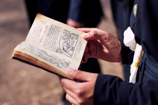 The hands of an elderly religious woman, holding and reading the Holy Bible, reveal its symbolism, words, illustrations, details, and the crucifix in her hands, with great devotion.