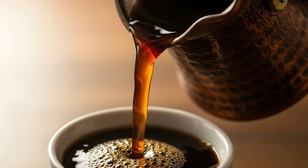 Freshly brewed hot coffee pouring from a traditional copper cezve into a white ceramic cup, creating rich golden foam and bubbles.