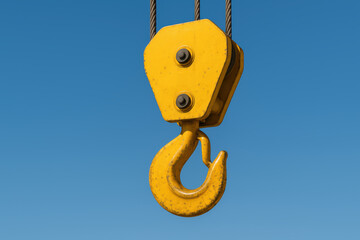 Bright yellow crane hook with steel suspension under a clear blue sky industrial equipment ready for heavy lifting emphasizing strength and machinery