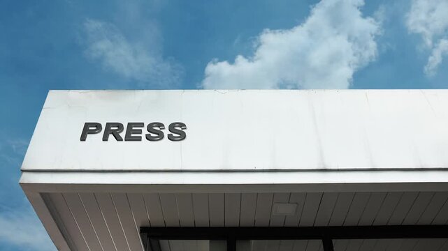 A Press word sign displayed on a news or media organization building under a clear blue sky, symbolizing journalism, media, communication, reporting, and information services