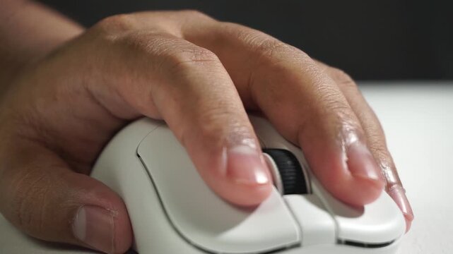 White computer mouse moves from blur to focus as it glides and clicks on desk surface, macro shot emphasizing motion and precision in soft natural lighting.