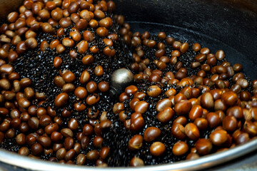 Chestnuts are roasted in a large pan.
