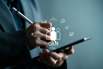 Businessperson using tablet with virtual CRM interface, concept of customer relationship management, business analytics, data-driven marketing, and digital sales strategy for corporate growth.