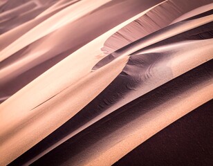 Close-up angled view of gently curving, textured sand dunes. Soft light and shadows create depth. Subtle color variations