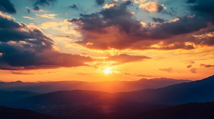 A vibrant sunset over a mountain range with a hazy sky, casting warm, golden hues over the landscape.