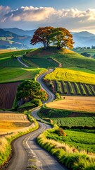 A winding road snakes through rolling, vibrant green and gold fields under a partly cloudy sky. A large tree sits atop the hill